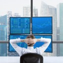 Confident trader looking at 4 monitors with Froex charts and data.